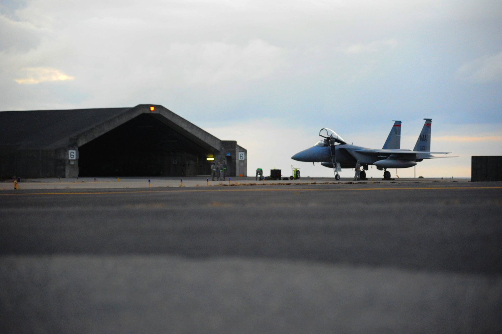 美國空軍 F-15C 戰機停放於硬化機堡前，維修人員在旁作業