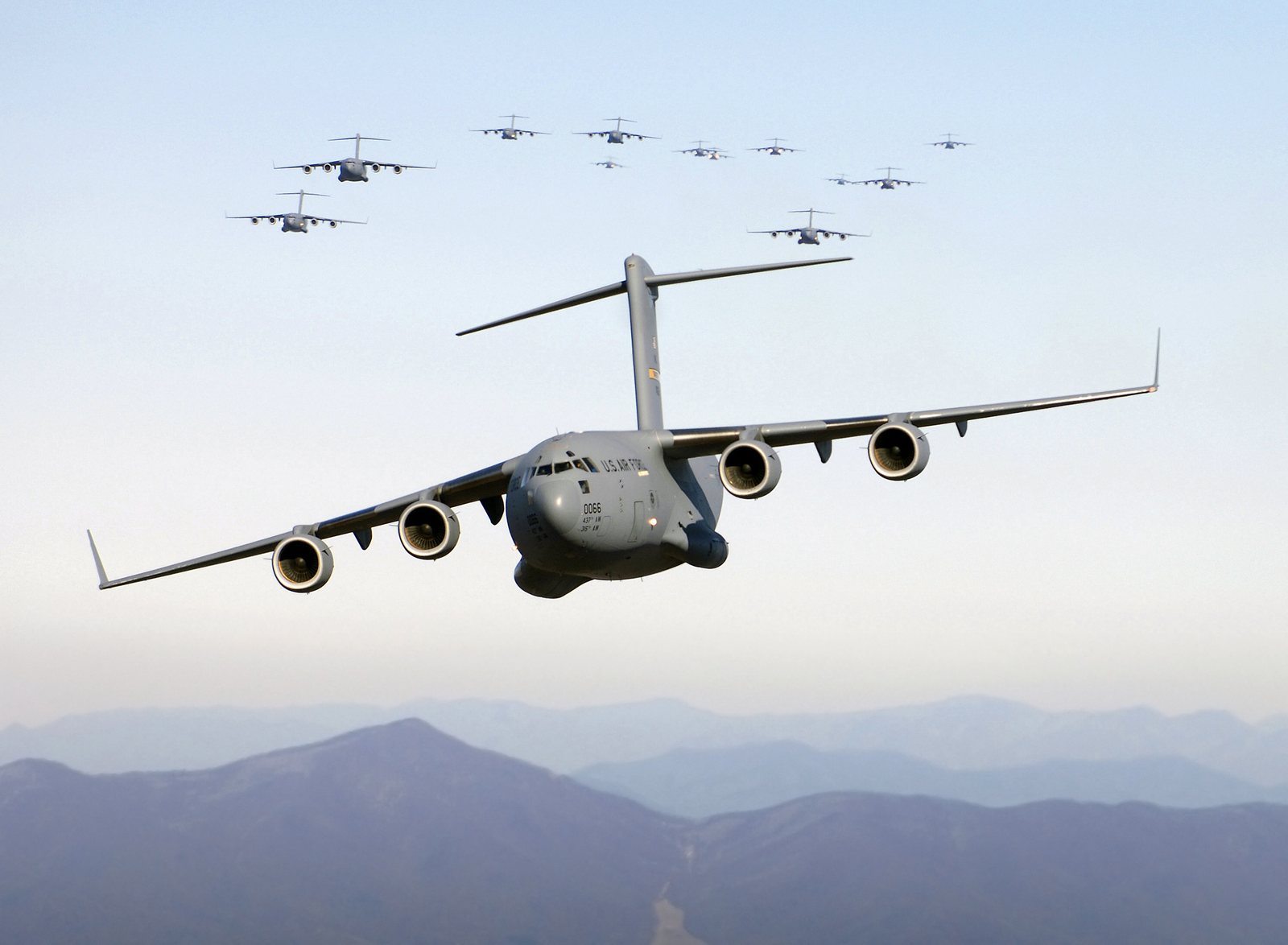 多架 C-17 Globemaster III 運輸機於山區上空低空戰術編隊飛行