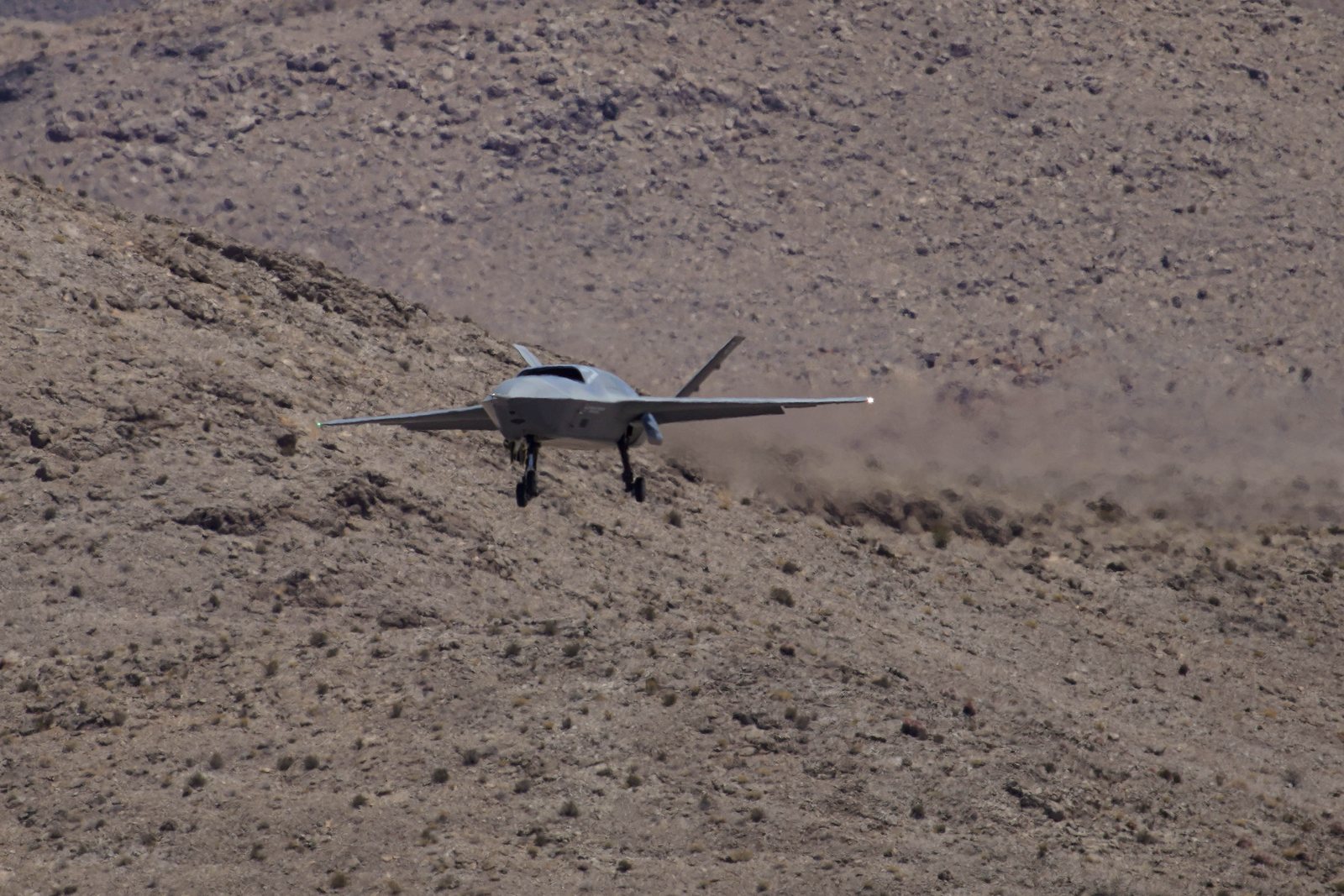 一架 YFQ-42A 協同作戰機在沙漠地形上空放下起落架準備降落